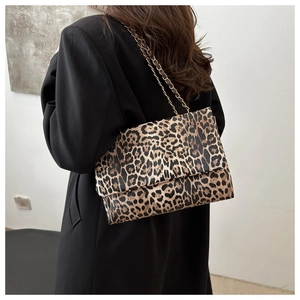 Close-up of leopard print shoulder bag with gold chain strap on a black blazer