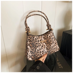 Dettaglio di borsa sottobraccio leopardata con finiture dorate e manici sottili