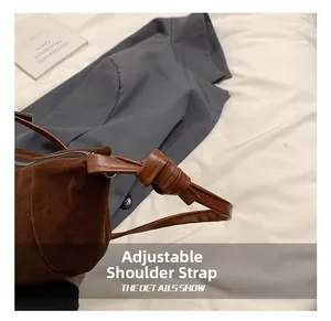 Detail of dark brown suede crescent bag featuring unique adjustable knotted shoulder strap