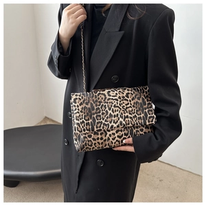 Schicke Umhängetasche mit Leopardenmuster und goldener Kette über schwarzem Blazer