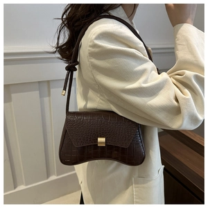 Detail of dark brown crocodile embossed shoulder bag with vintage gold metal buckle