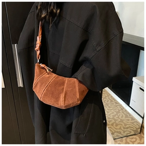 Detail of a brown suede crescent bag with vertical pleated stitching and knot strap