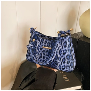 Dettaglio borsa a spalla leopardata blu con barre dorate e manico in corda con nodi