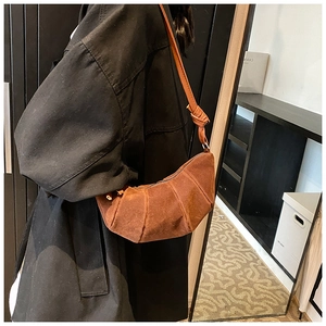 Detailed side view of a brown suede dumpling bag with a knotted strap on model
