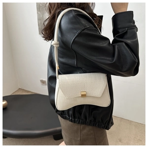 Detail of white crocodile texture bag with gold buckle and unique rope knot shoulder strap