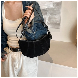 Detail of black suede crescent bag showing the trendy knot shoulder strap design
