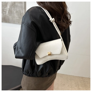 Close-up of white crocodile pattern underarm bag with gold metal buckle and knot strap