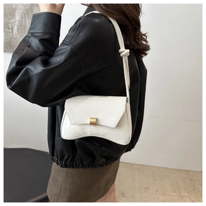 Detail of white crocodile embossed underarm bag with gold buckle and hourglass bottom