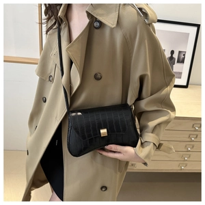 Close-up of black faux crocodile embossed leather shoulder bag with gold metal buckle