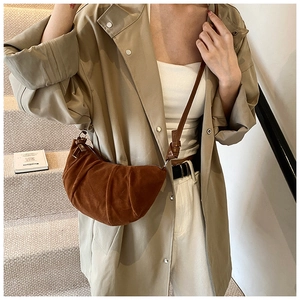 Detail of a pleated brown crescent handbag with a soft suede-like texture and strap