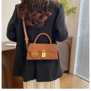 Détail du sac bandoulière vintage en daim marron avec fermoir doré et pendentif