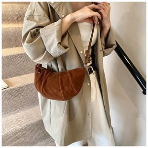 Detail of caramel brown suede pleated dumpling bag with elegant draped texture and zipper