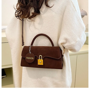 Détail d'un sac bandoulière en daim marron foncé avec fermoir doré et pendentif mode
