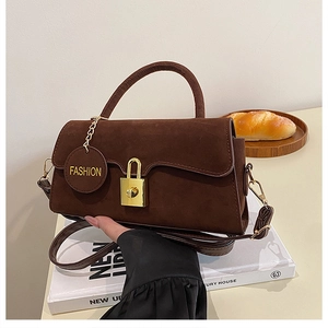 Vue détaillée du sac en daim marron avec fermoir doré vintage et étiquette ronde