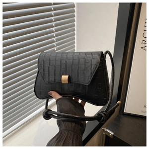 Close-up of black crocodile pattern faux leather bag with gold buckle and knot detail