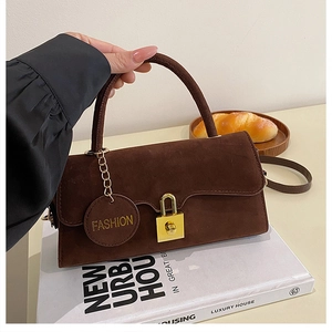Gros plan d'un sac à main rétro en daim marron avec boucle dorée et étiquette de mode