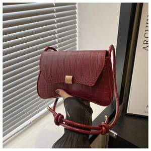 Detailed view of dark red crocodile embossed leather texture and gold square metal lock
