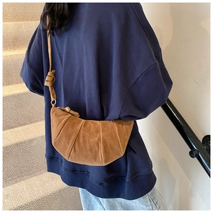 Detailed close-up showing the soft suede texture and folded knot design of the brown moon bag