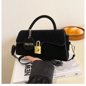 Détail d'un sac à main en daim noir avec boucle dorée et bandoulière amovible