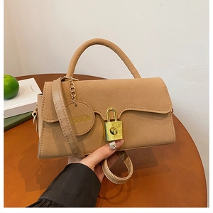 Détail du sac bandoulière en daim kaki avec boucle dorée et étiquette de mode