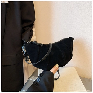Detail of black crescent suede crossbody bag with elegant pleats and knotted strap detail