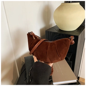 Detailed view of a brown suede dumpling bag featuring pleated texture and zipper closure