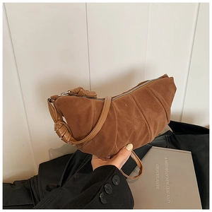 Detailed view of brown suede dumpling bag with knot handle and pleated design