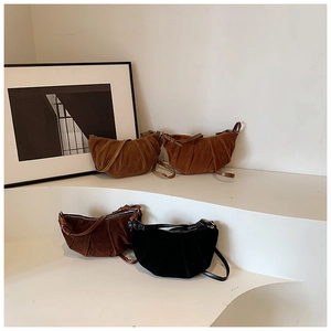 Minimalist half-moon pleated crossbody bags in brown and black on white display stand