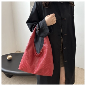 Detail of red woven leather tote bag with classic intrecciato texture shown on shoulder