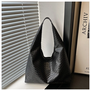 Détail du sac hobo tissé noir avec une bandoulière large au design minimaliste