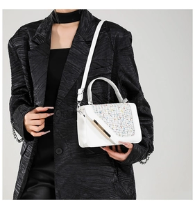 Dettaglio borsa a tracolla bianca con inserto in tweed colorato su modella in blazer nero