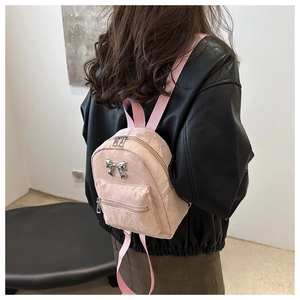 Mini sac à dos rose en nylon avec nœud argenté et poche avant porté par un mannequin
