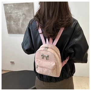 Détail d'un mini sac à dos en nylon rose avec un nœud en métal sur une veste en cuir