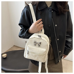 Détail d'un mini sac à dos blanc avec matière texturée et un nœud métallique argenté