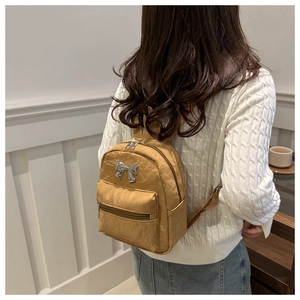 Vue arrière d'un mannequin portant le petit sac à dos en nylon kaki avec nœud argenté