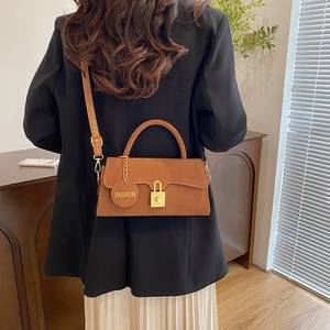 Sac bandoulière vintage marron en daim avec boucle dorée porté par un mannequin