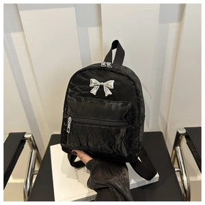 Détail d'un mini sac à dos en nylon noir avec un nœud métallique argenté et texture plissée