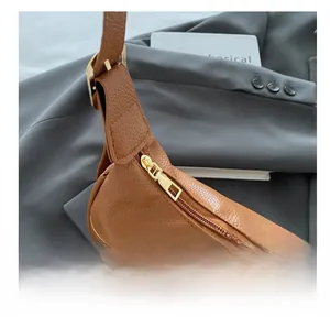 Detail of premium brown lychee pattern leather with a smooth gold metal zipper closure
