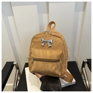 Détail du mini sac à dos jaune avec nœud en métal argenté et tissu en nylon gaufré