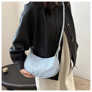 Detail of sky blue lychee grain leather crossbody bag with gold hardware and logo