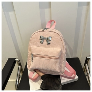 Détail d'un sac à dos rose en nylon avec nœud argenté et texture froissée chic