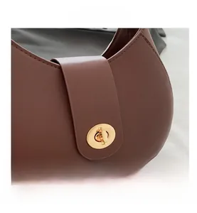 Close-up of brown leather bag with elegant golden round twist lock and neat stitching