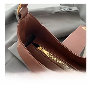 Detail shot of smooth golden metal zipper and brown leather texture of the shoulder bag