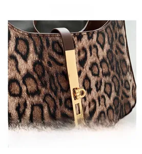 Détail d'un sac léopard avec fermoir en métal doré et lanière de fermeture en cuir marron