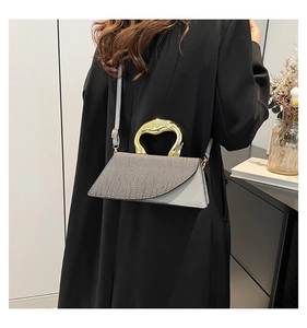Detail of grey crocodile embossed handbag featuring unique liquid-gold metal handle