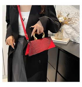 Detail of red croc-embossed triangular handbag with gold U-handle and detachable strap