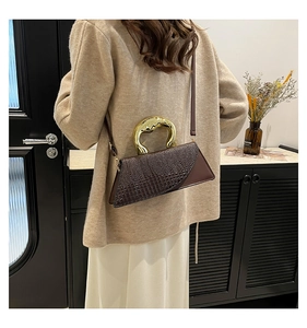 Detailed view of crocodile pattern leather bag with artistic gold metal handle