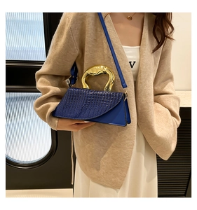 Detail of dark blue embossed leather bag with unique geometric gold metal handle