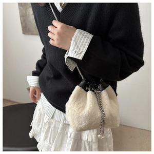 Detail of plush bucket bag featuring soft faux fur texture and silver metal chain strap