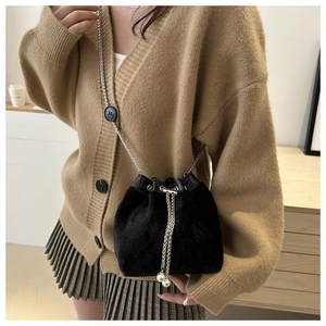 Detail of black velvet bucket bag featuring elegant pearl drawstring and silver chain strap